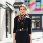 Elegantní žena v černých šatech s výraznými doplňky ve městě s rozmazaným pozadím
